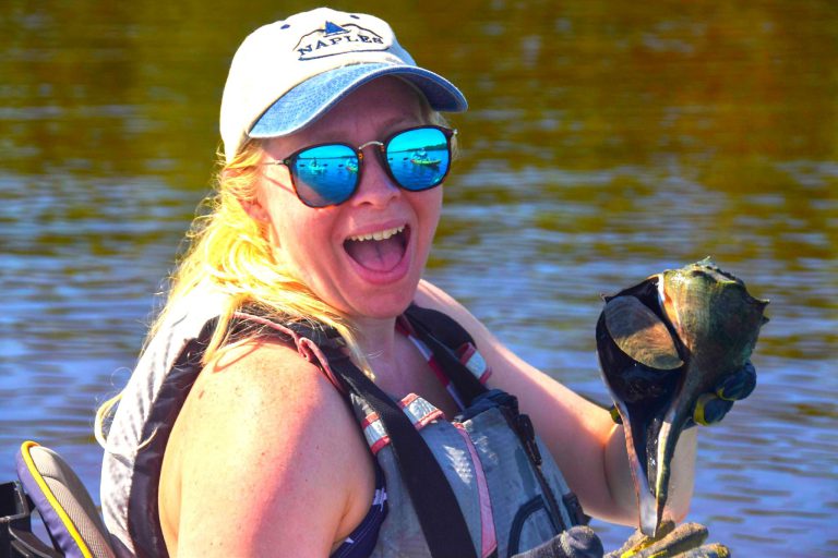 a person wearing a helmet and sunglasses in front of a body of water
